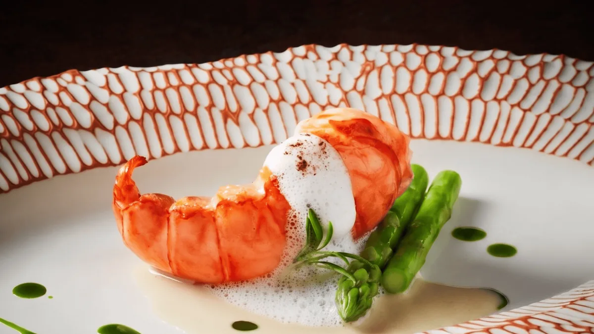 กุ้งมังกรกับผักและซอสบนจานลายส้มขาวของร้านอาหาร (R-HAAN)