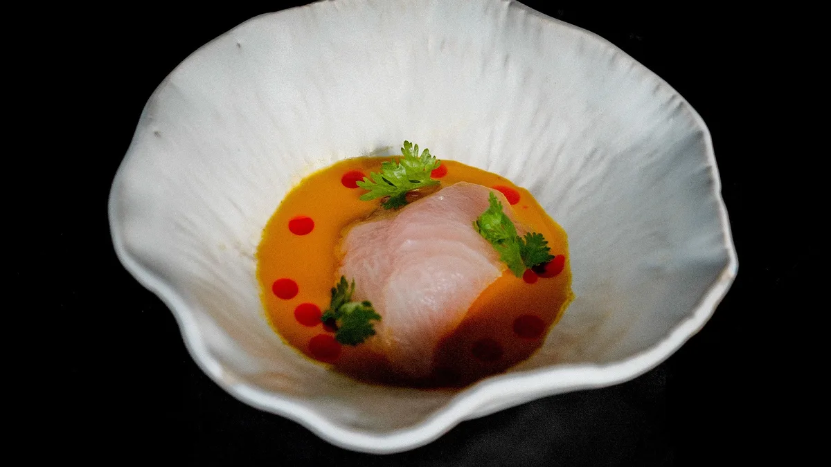 ปลาดิบในซอสสีส้มบนจานเซรามิกทรงคลื่นที่ร้าน 80/20