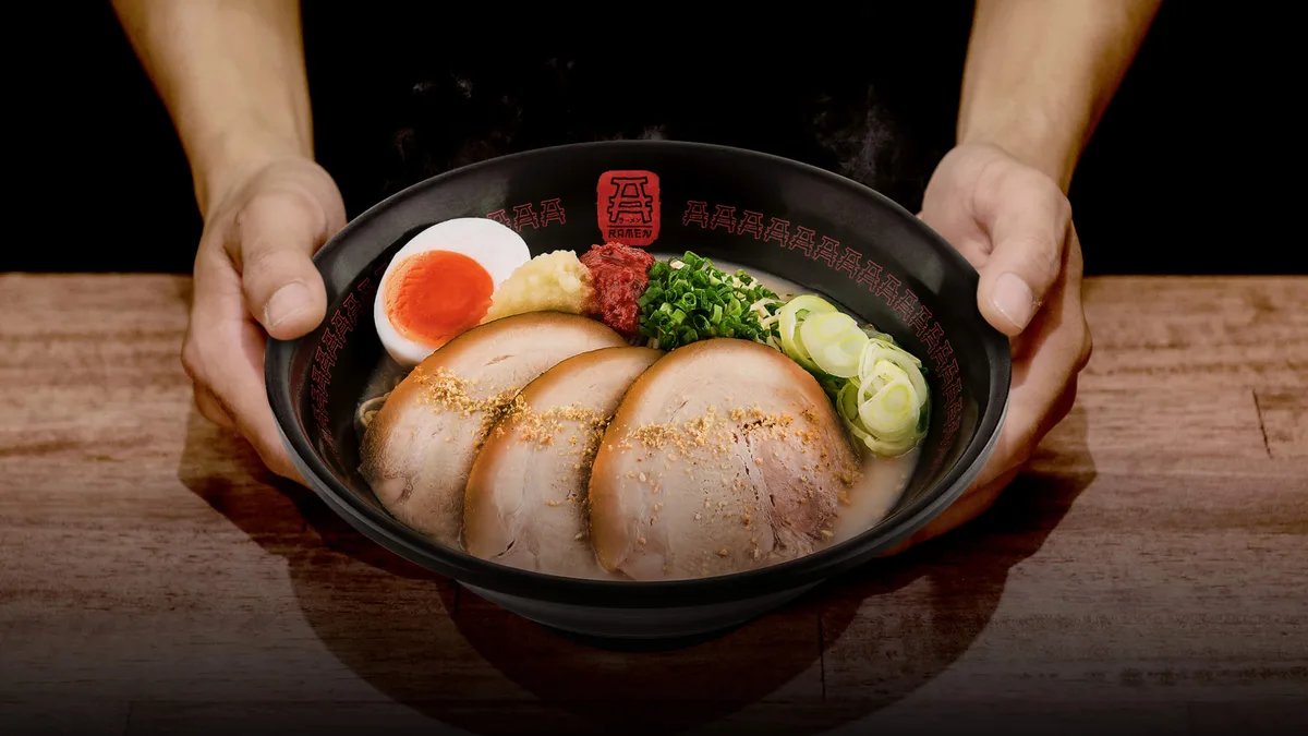 ราเมนทงคตสึหมูชาชูและไข่ยางมะตูมของเอ ราเมน ในชามที่ประคองด้วยสองมือ