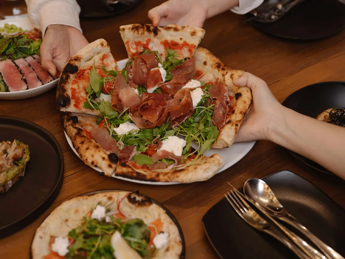พิซซ่าแป้งบางหน้าแฮมพาร์มาและร็อกเก็ตบนโต๊ะไม้
