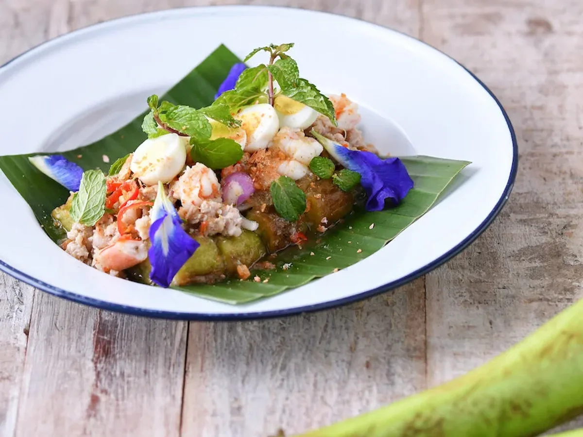 ยำกุ้งกับไข่และดอกอัญชันบนใบตองในจานขาว