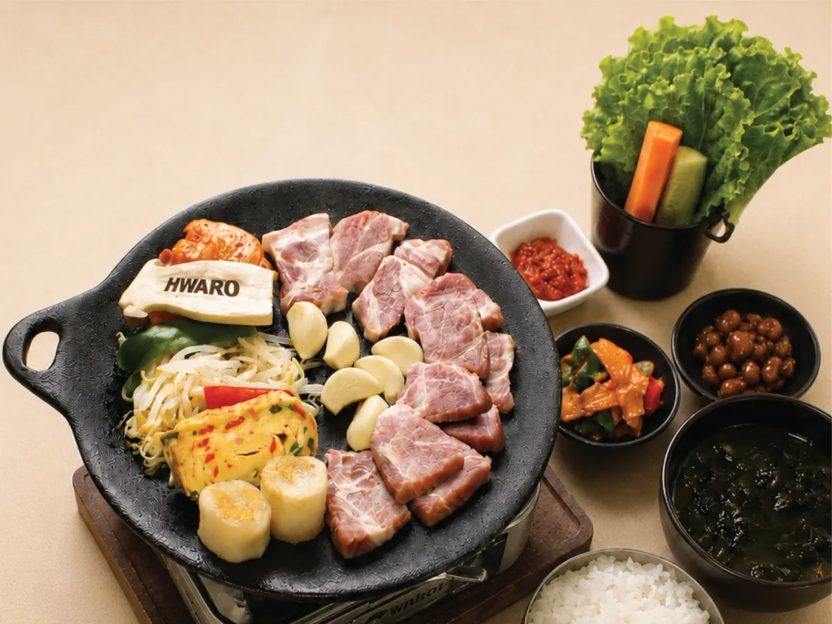 หมูสามชั้นและหมูสไลซ์บนกระทะเหล็กพร้อมข้าวและเครื่องเคียงเกาหลี