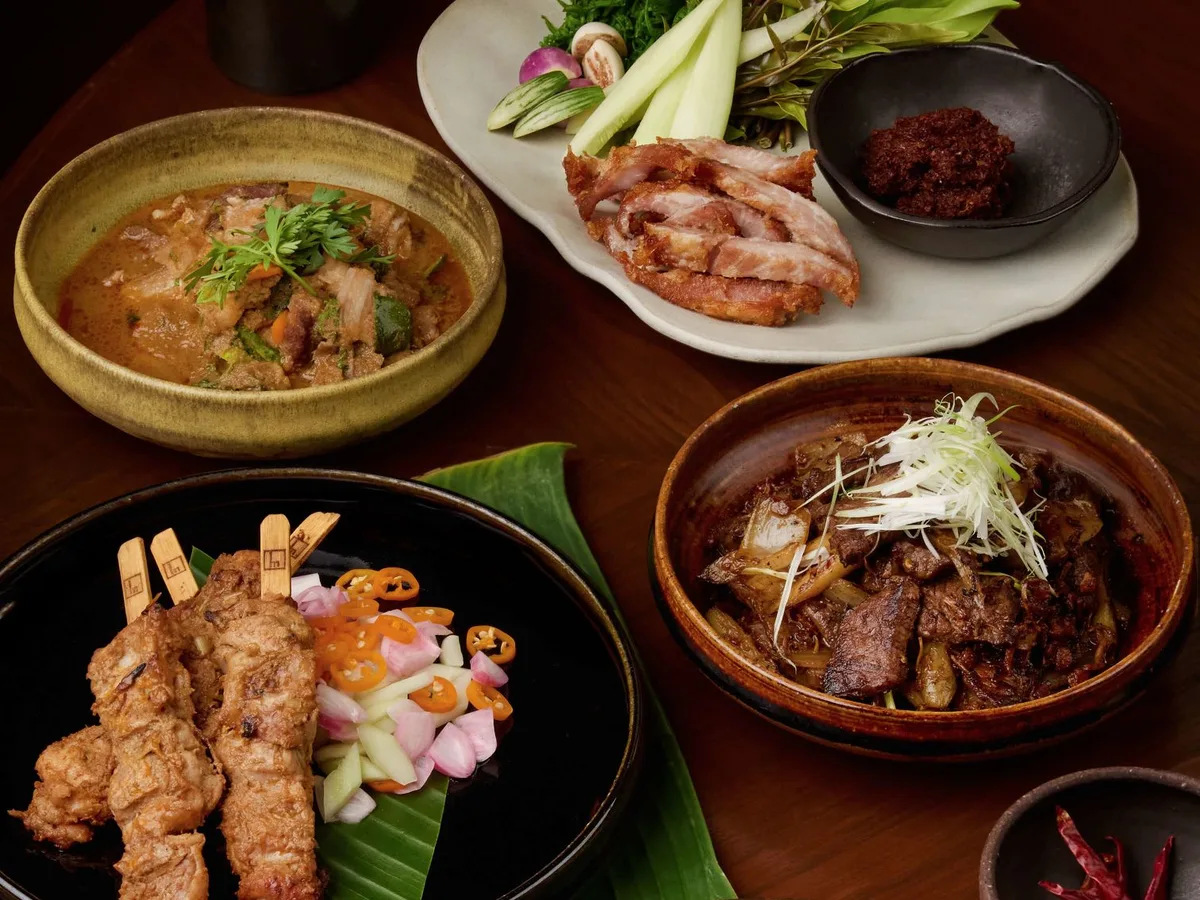 สำรับอาหารไทยหลายจาน มีแกง หมูปิ้งเสียบไม้ และน้ำพริก