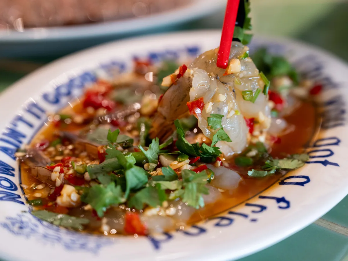 กุ้งแช่น้ำปลาราดน้ำยำพริกกระเทียมบนจานลายครามของร้าน