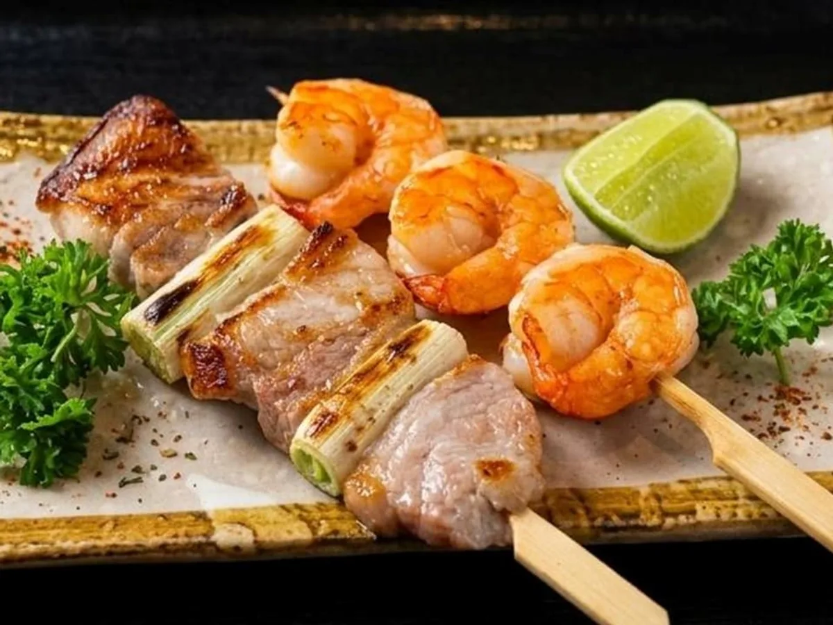 ไม้ย่างหมูสลับต้นหอมญี่ปุ่นกับกุ้งย่างบนจานยาว