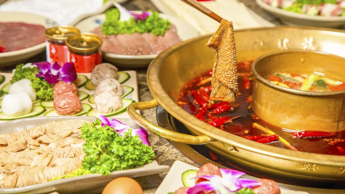หม้อไฟหม่าล่าทองเหลืองของเสี่ยวหลงข่าน น้ำซุปพริกแดงล้อมด้วยจานเนื้อ ผัก และของลวก