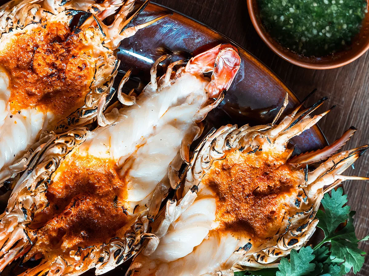 กุ้งแม่น้ำย่างผ่าครึ่ง มันกุ้งเยิ้ม วางบนเขียงไม้