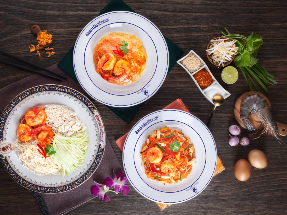 ผัดไทยกุ้งสามจาน ทั้งแบบห่อไข่และแบบเส้นผัด พร้อมเครื่องเคียงบนโต๊ะไม้