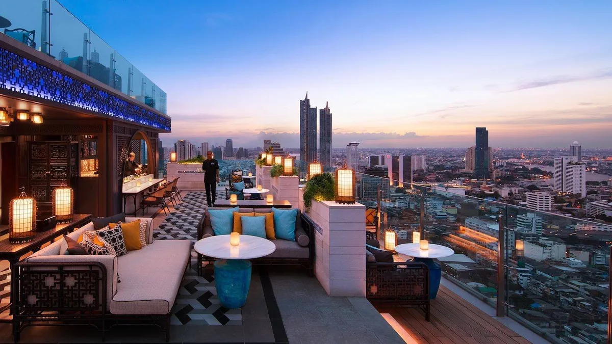 ระเบียงดาดฟ้าของ Yào Rooftop Bar ยามพลบค่ำ โซฟาและโคมไฟเหนือเส้นขอบฟ้ากรุงเทพฯ