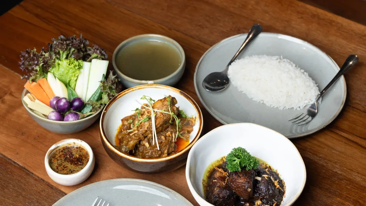 สำรับพม่าที่โย่ว โย่ว เล แกงหมู แกงเนื้อ ข้าวสวย ผักสดและน้ำพริกบนโต๊ะไม้